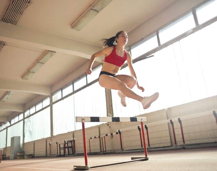 woman jumping over obstacle
